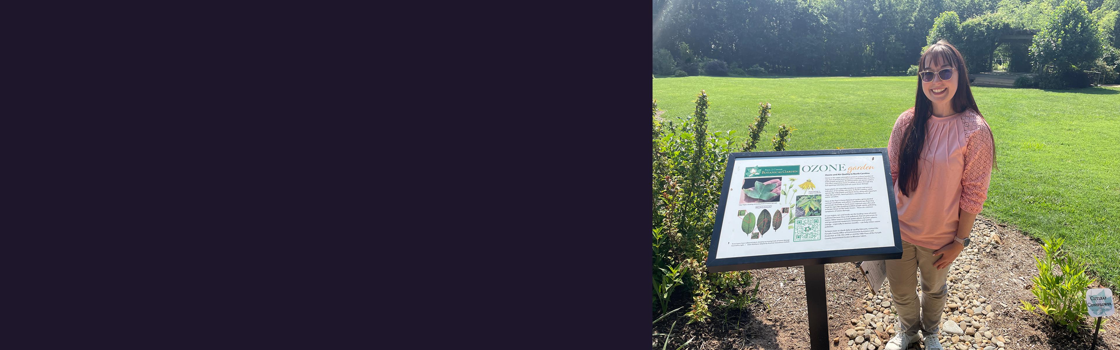 Sarah Coffey in front of an interpretive sign for the ozone garden