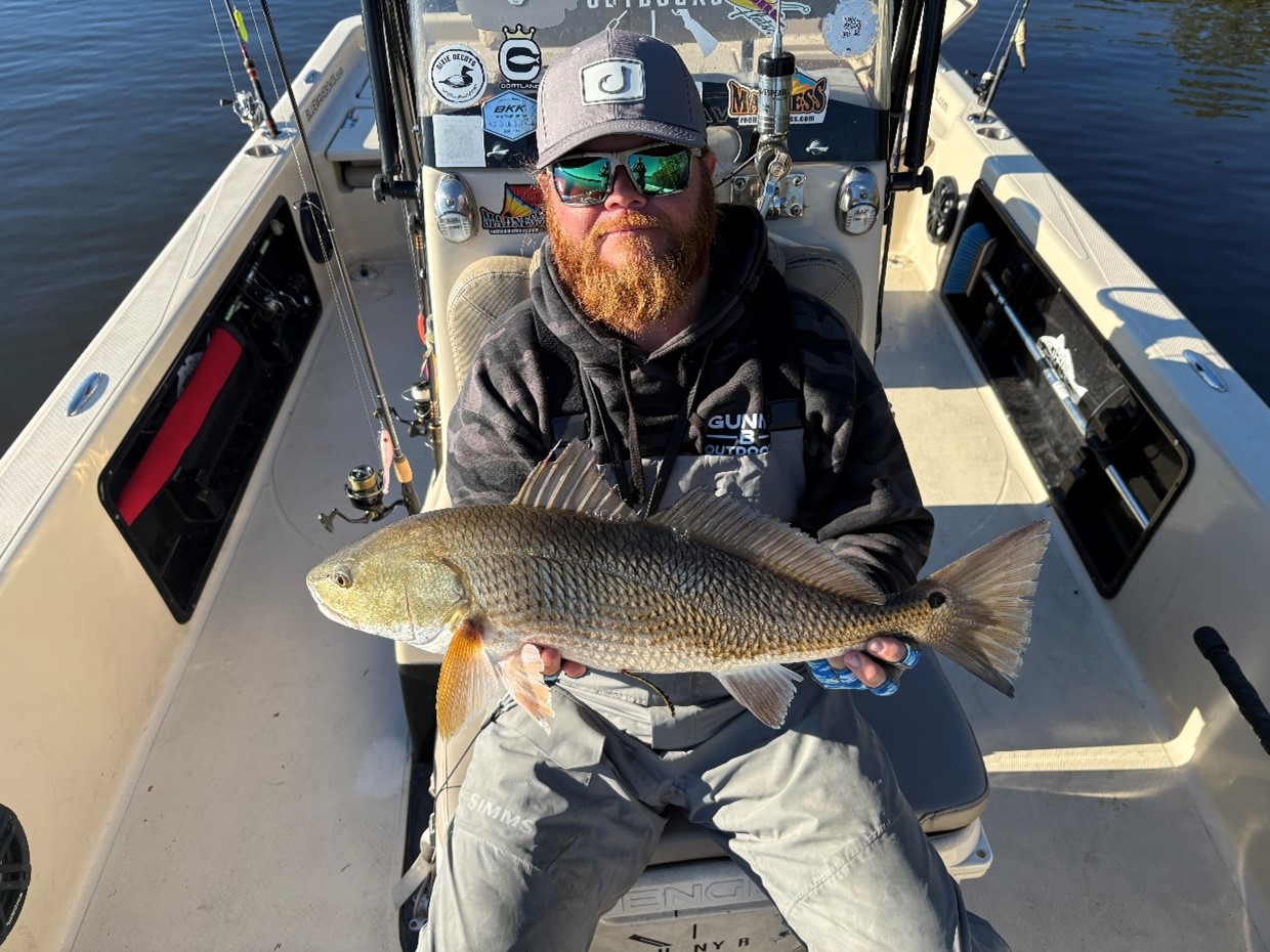 Brad Smith holds a red drum on a fishing boat.