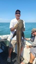 Man on a boat holds up a Cobia 