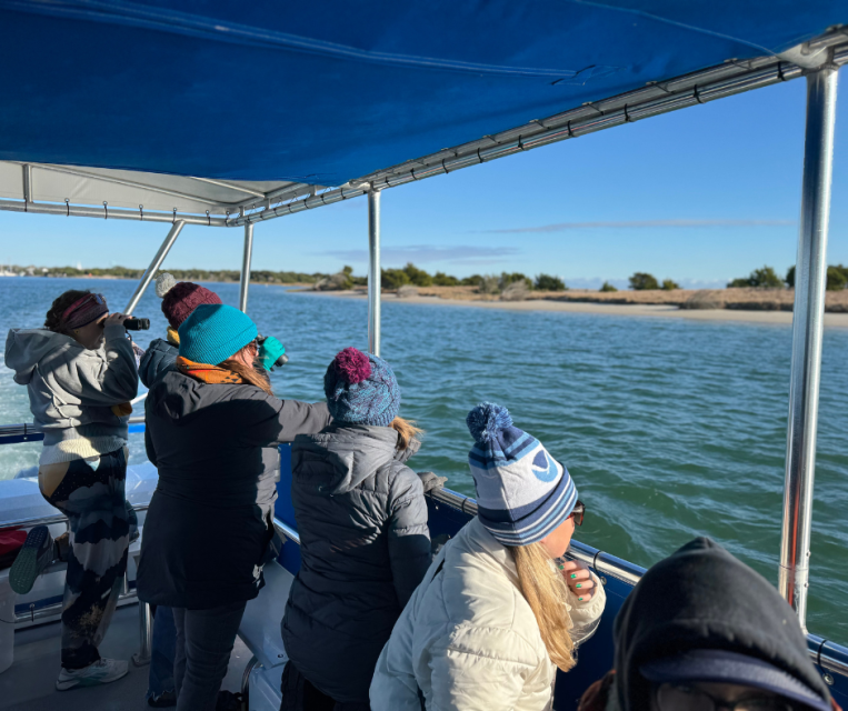 Group of people in beanies on a boat looking over the water
