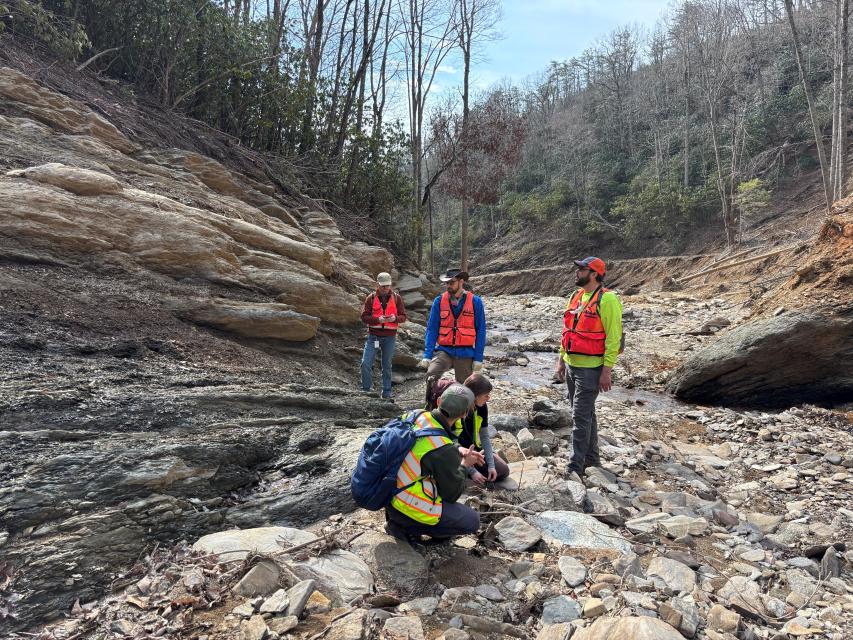 NCGS geologic mappers standing in a debris flow in western North Carolina. Image shows the land scoured down to exposed bedrock.