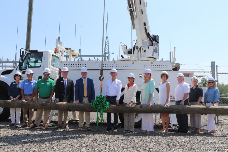 speakers and project stakeholders stand around electric pole to signify kickoff of project