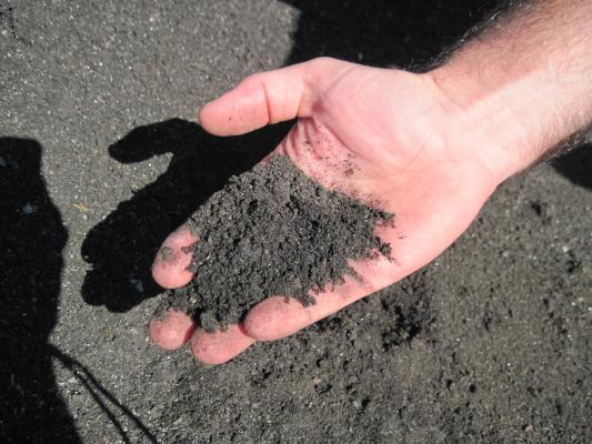 someone's hand holding grounded up shingles