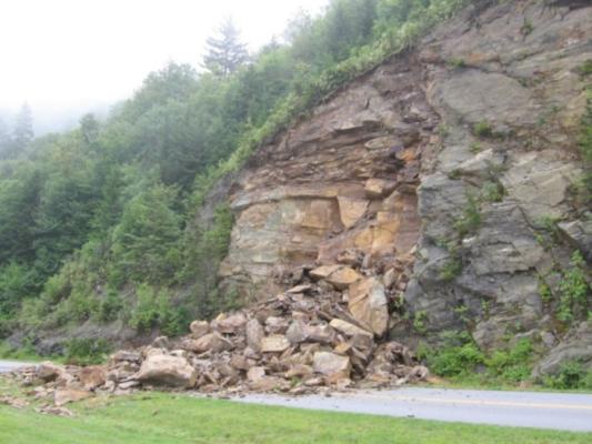 Photo a rock slide on the Blue Ridge Parkway in 2006. Rocks have fallen from a roadcut and cover the road surface, blocking road access.