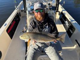 Brad Smith holds a red drum on a fishing boat.