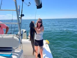 Woman holds up a cobia from a boat
