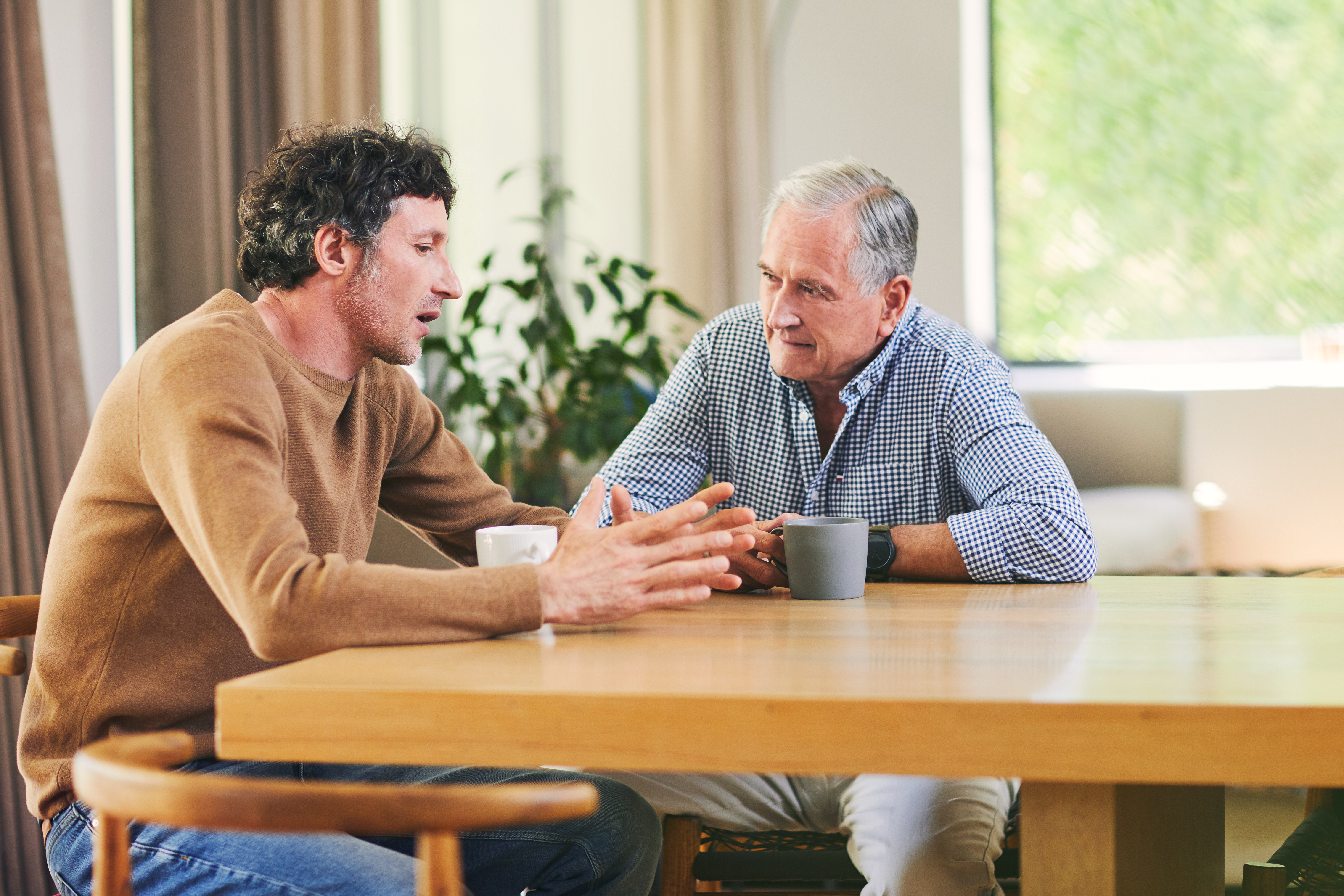 man sitting and talking with father at kitchen table