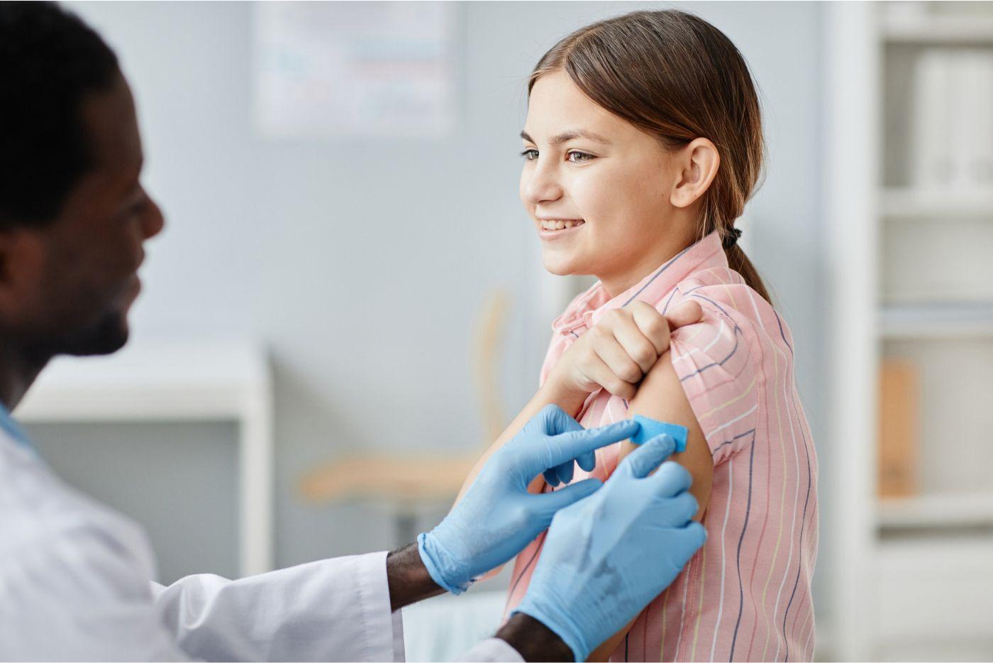 A doctor putting a band-aid on a child's arm. 