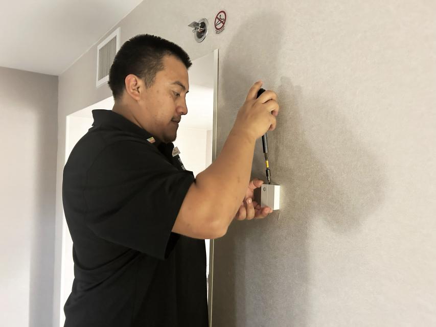 Jose Kovach replaces the battery in a hotel room in the Hilton Charlotte Airport hotel.