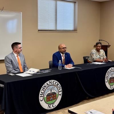 Secretary Sangvai, Deputy Secretary Michael Leighs sit at table during visit with Chowan County DSS Director