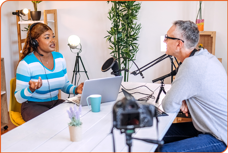 A young African American female thoughtfully expresses her ideas as an older white male listens intently during a video podcast discussion.
