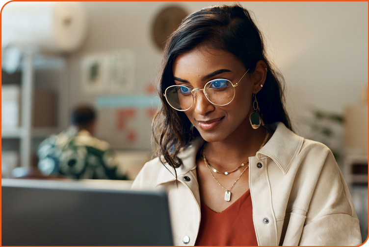 A self-assured young Indian woman focuses on a computer screen, confidently writing copy for her website content.