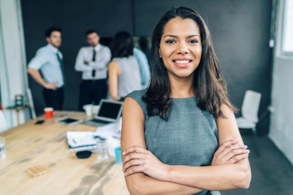 Focus on a professional woman with teammates chatting in the background