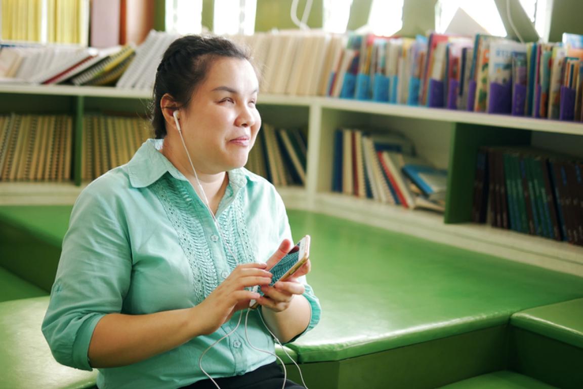 Asian woman with visual impairment enjoys using a smart phone with voice accessibility