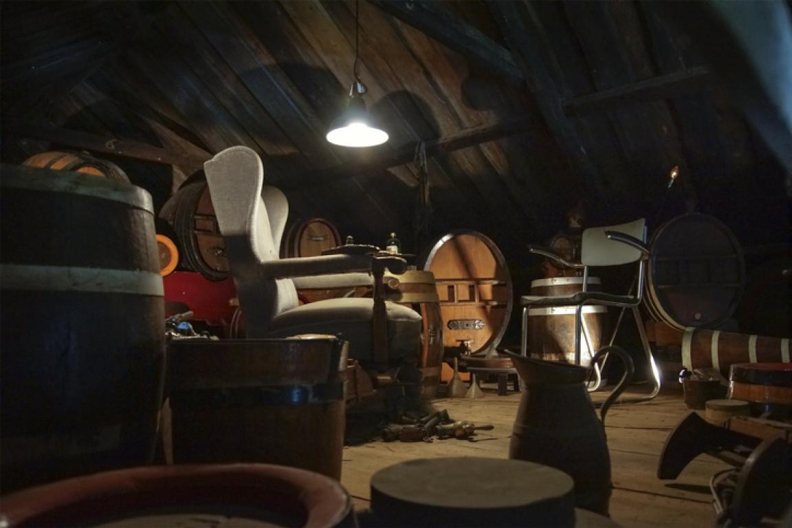 A dusty attic filled with old furniture illuminated by a single light.