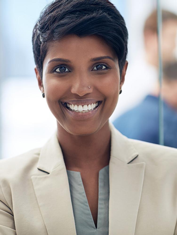Woman in business suit in an office, coworkers in the background