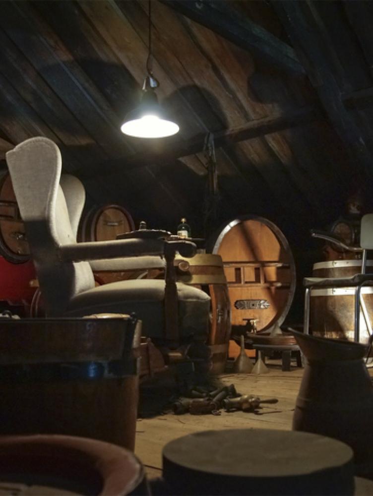 A dusty attic filled with old furniture illuminated by a single light.