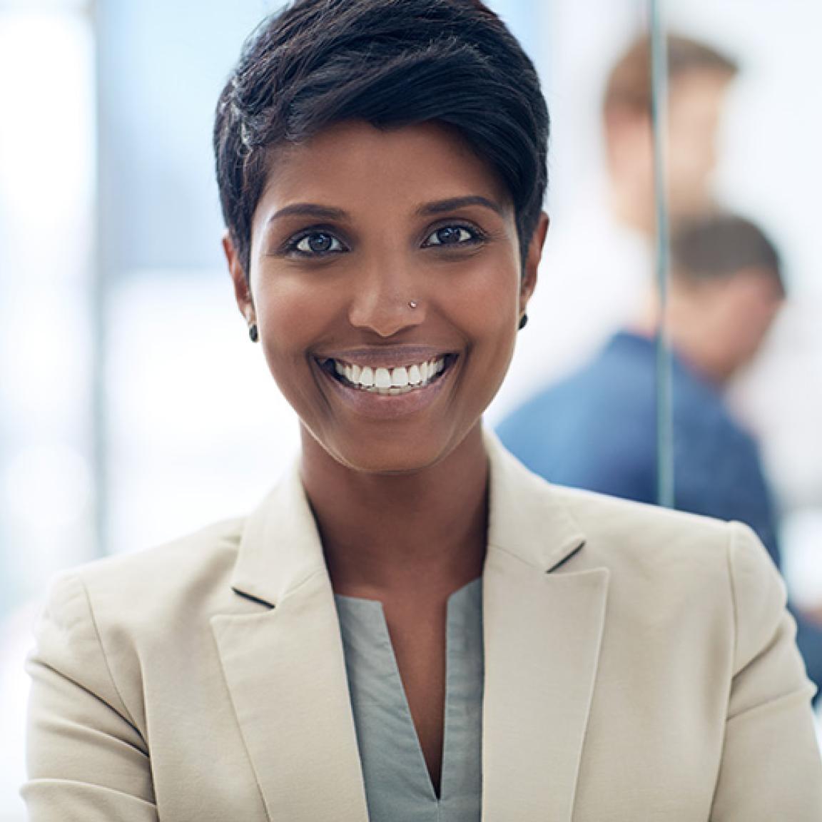 Woman in business suit in an office, coworkers in the background
