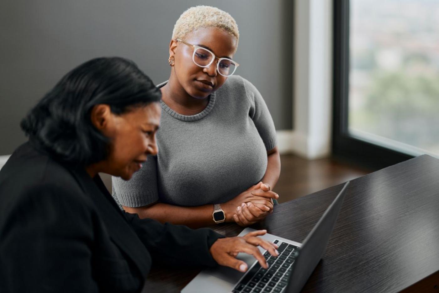 One woman navigates a website on a laptop while another observes how she uses the site.
