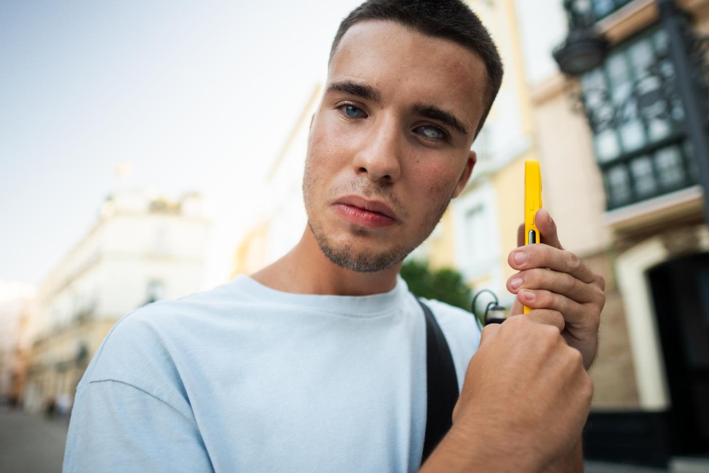 A young man with a visual disability listens to a screen reader on his mobile phone.