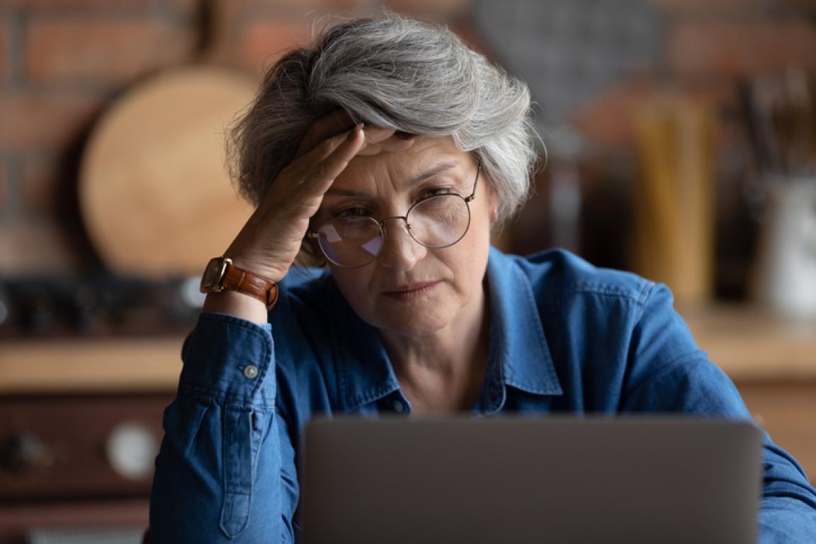 Elderly lady looking concerned at laptop