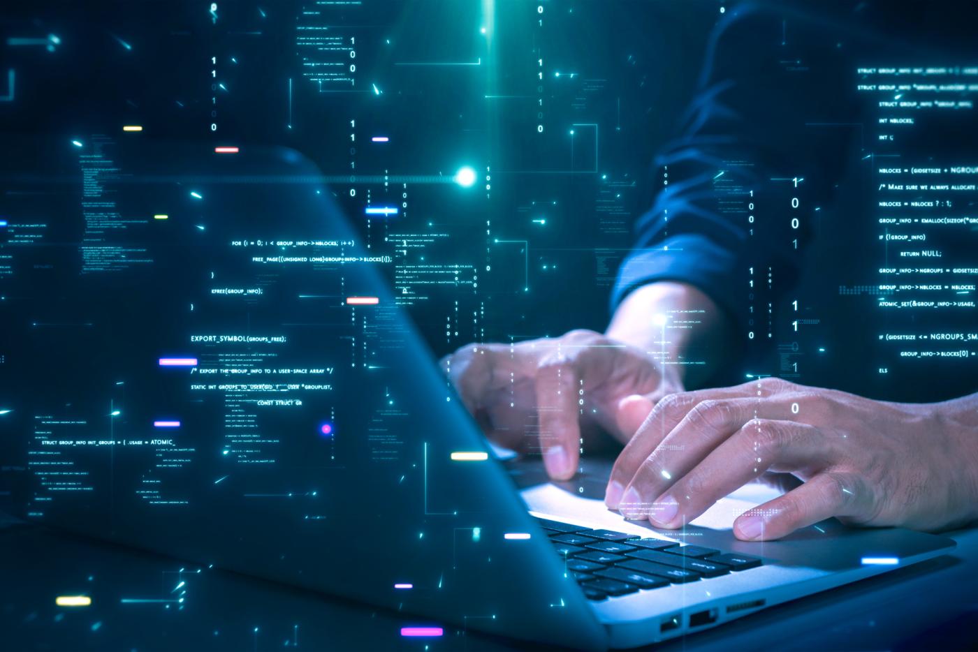 Close-up of hands typing on a laptop with glowing programming code and binary graphics, symbolizing cybersecurity technology coding or software development.