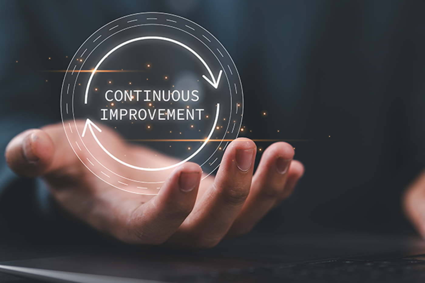 Picture of a man's hand pretending to hold a circle graphic saying Continuous Improvement.
