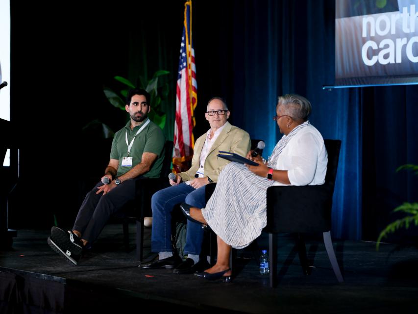 Chief Information Security Officer seated on stage with two other speakers moderating a discussion during the N.C. Digital Government Summit