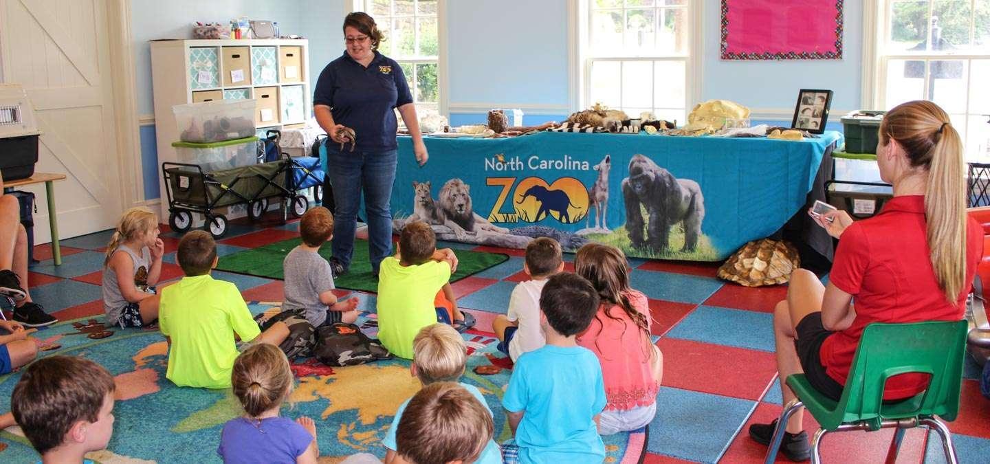 A NC Zoo educator shows a turtle to an elementary school classroom.
