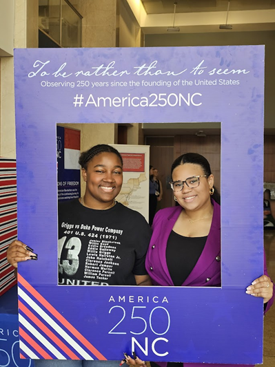 Students pose with the America 250 NC sign.