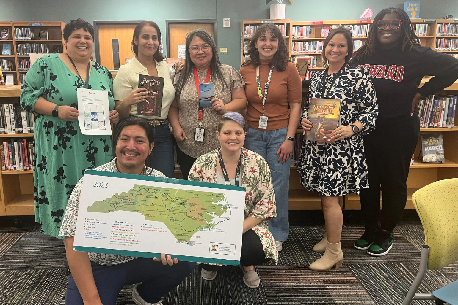 Hugo holds up a NC map with a group of teachers and DNCR educators.