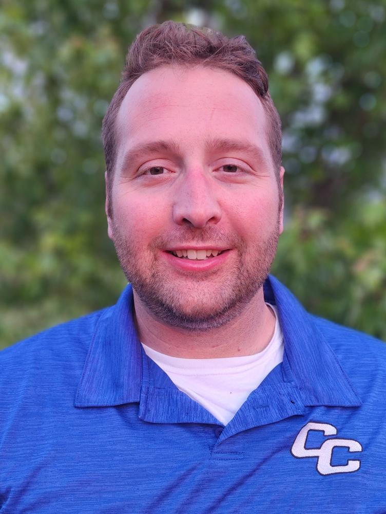 a white man in a blue polo smiles at the camera