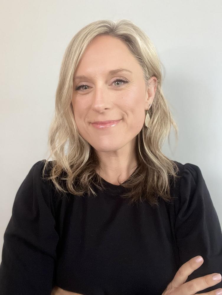 a woman with blonde hair and a black sweater smiles at the camera