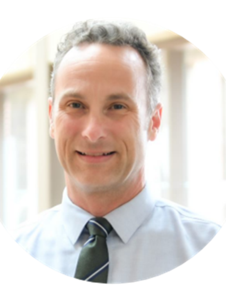 a white man in a tie smiles at the camera
