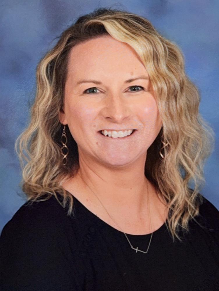 a blonde woman in a black sweater smiles at the camera
