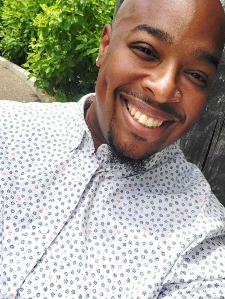 An African American man in a white shirt smiles at the camera