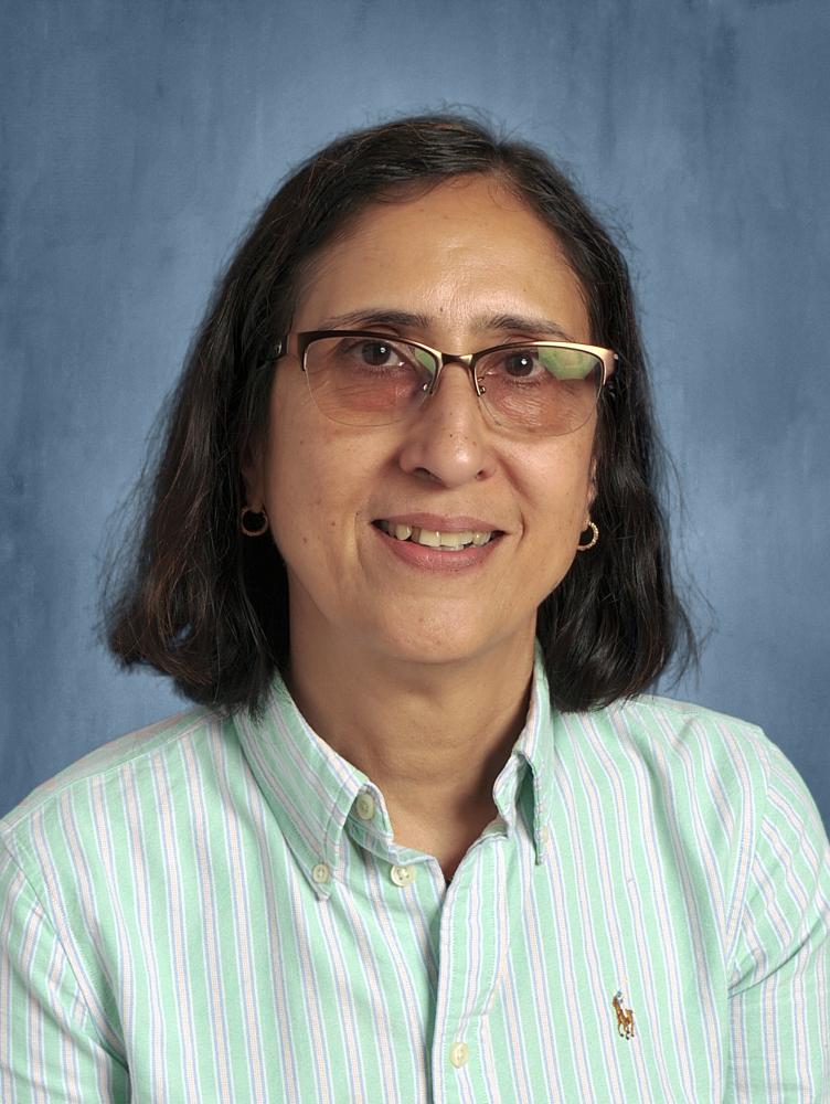 a woman with shoulder length brown hair wears glasses and smiles at the camera