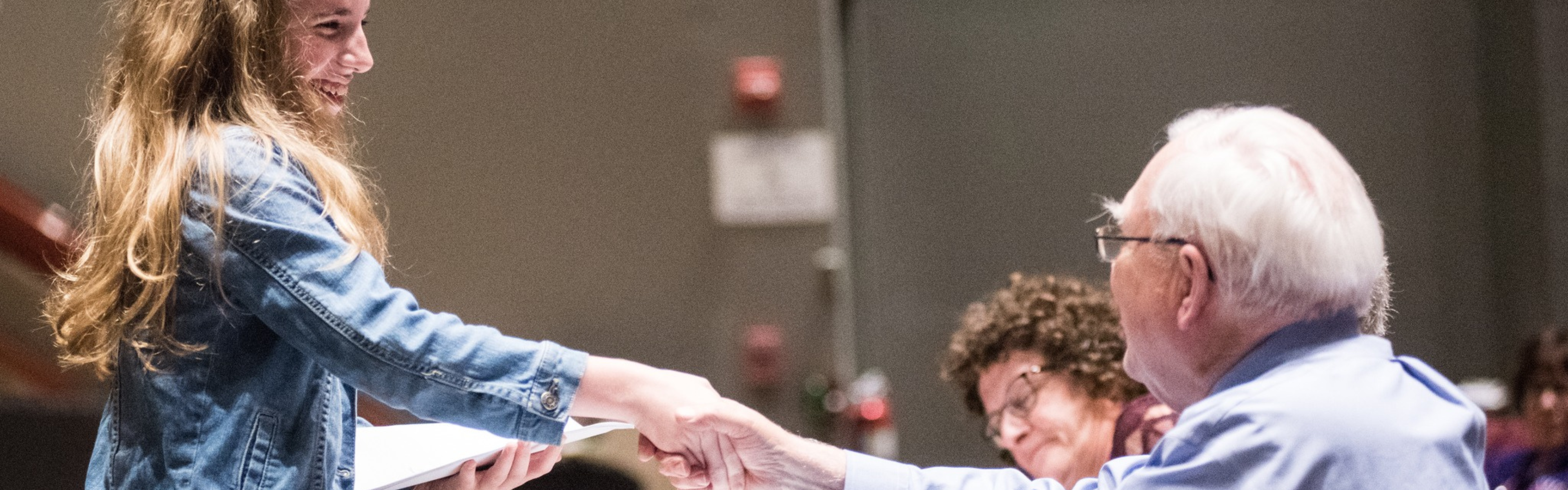A History Day student smiles and shakes hands with one of her judges.