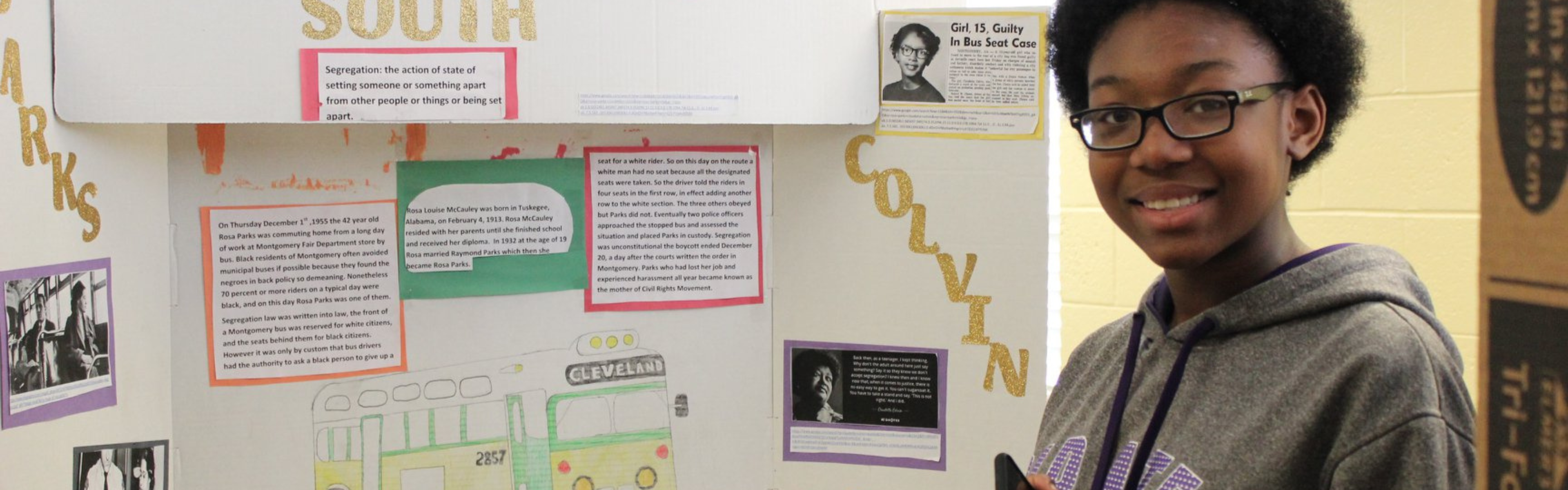 A NHD student smiles and stands in front of her exhibit.