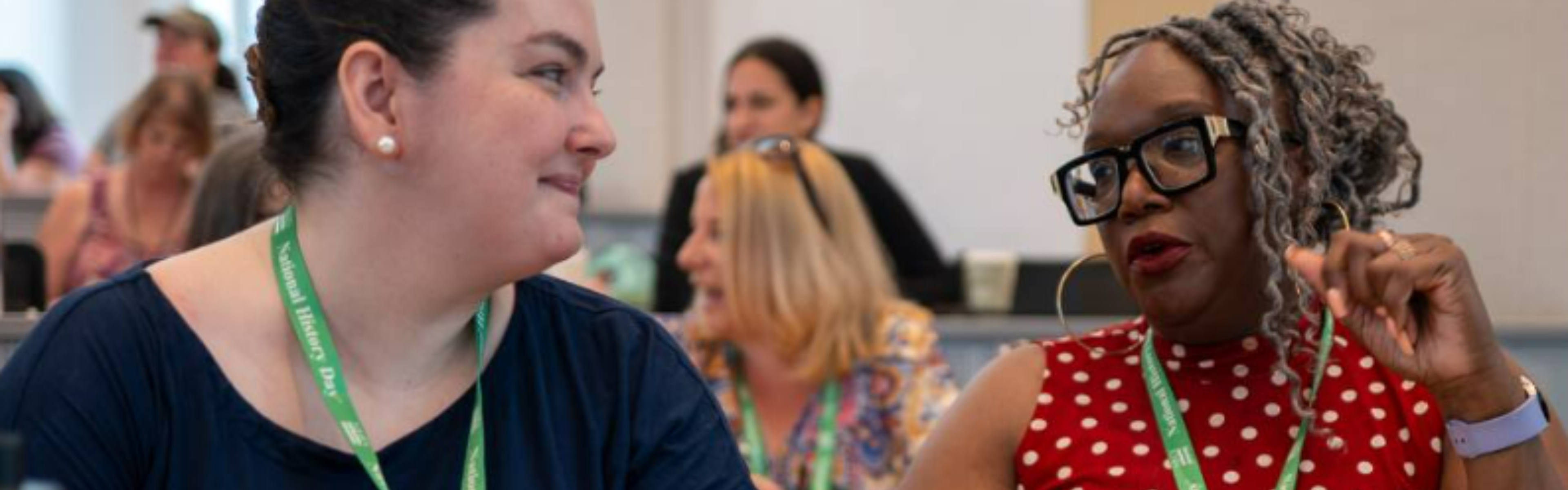 Two History Day teachers smile at each other as they talk at a teacher workshop.