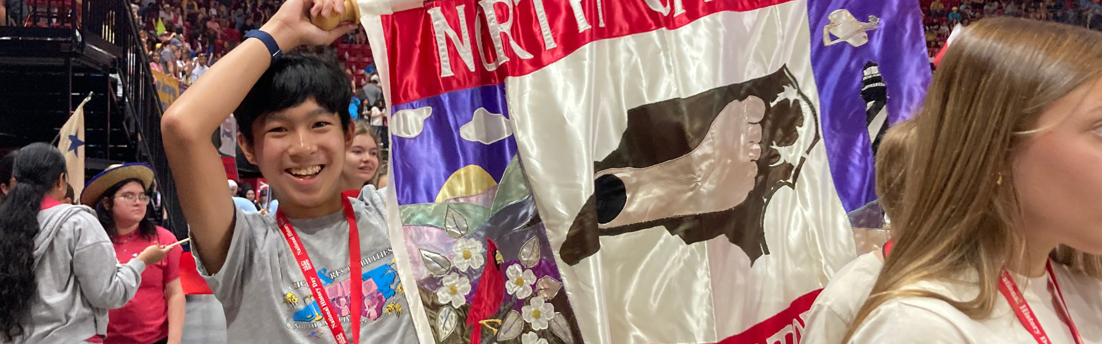 A History Day student holds the North Carolina banner while smiling during the parade of students at the national contest.