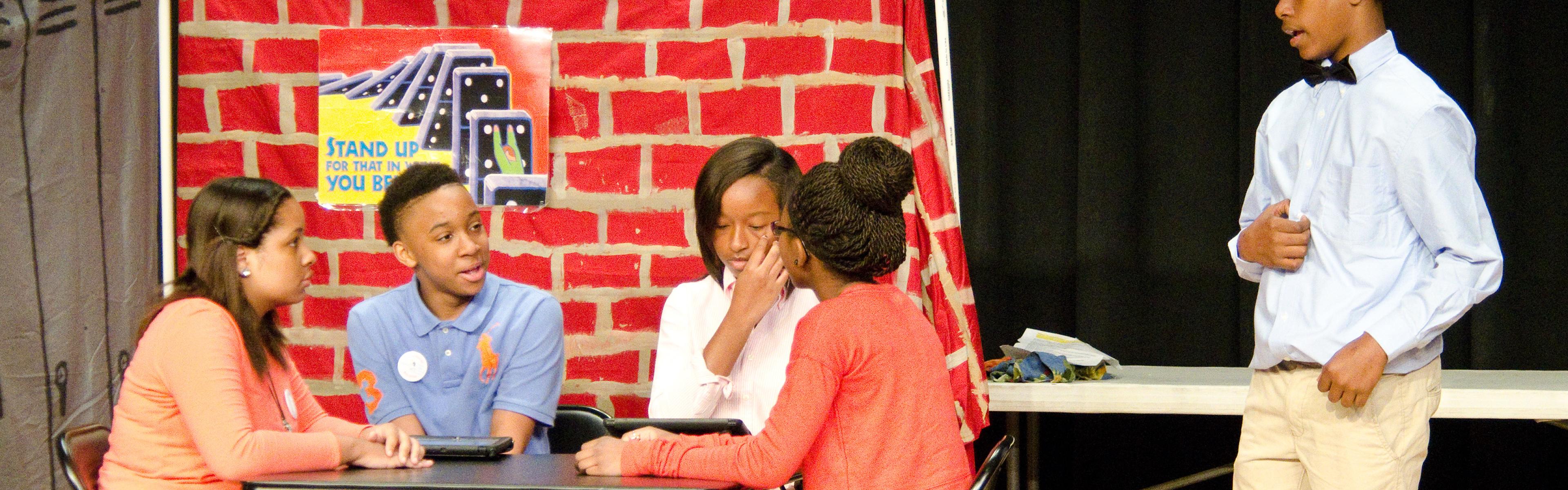 5 students on stage acting out their historic performance.