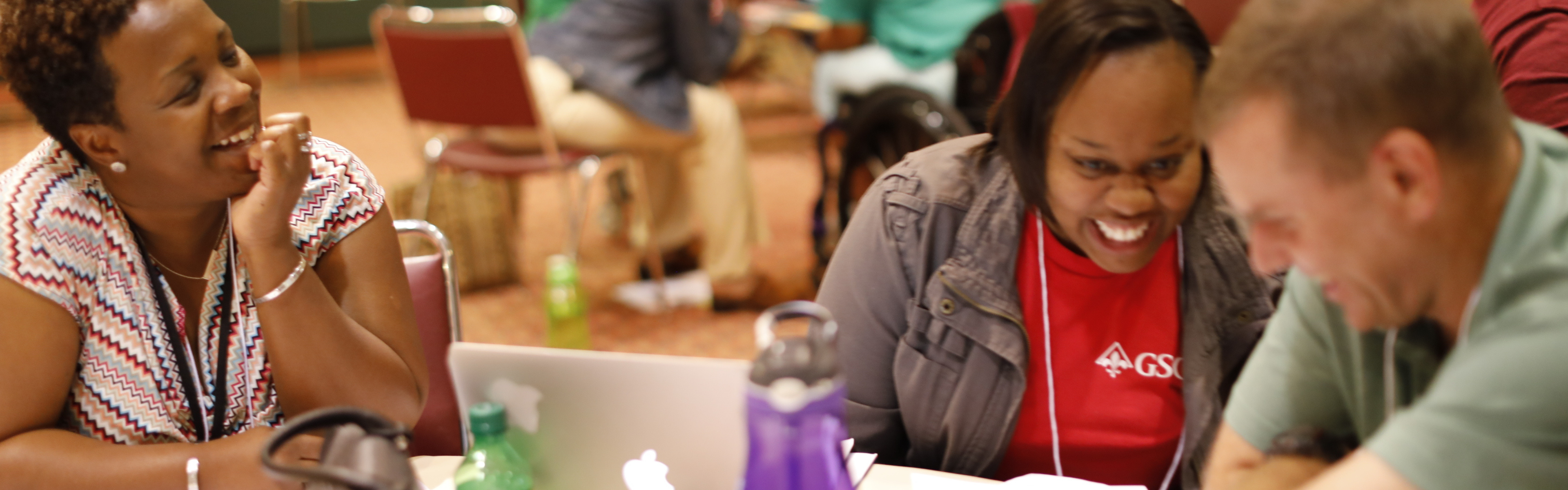 Teachers laugh around a table during a DNCR professional development workshop.
