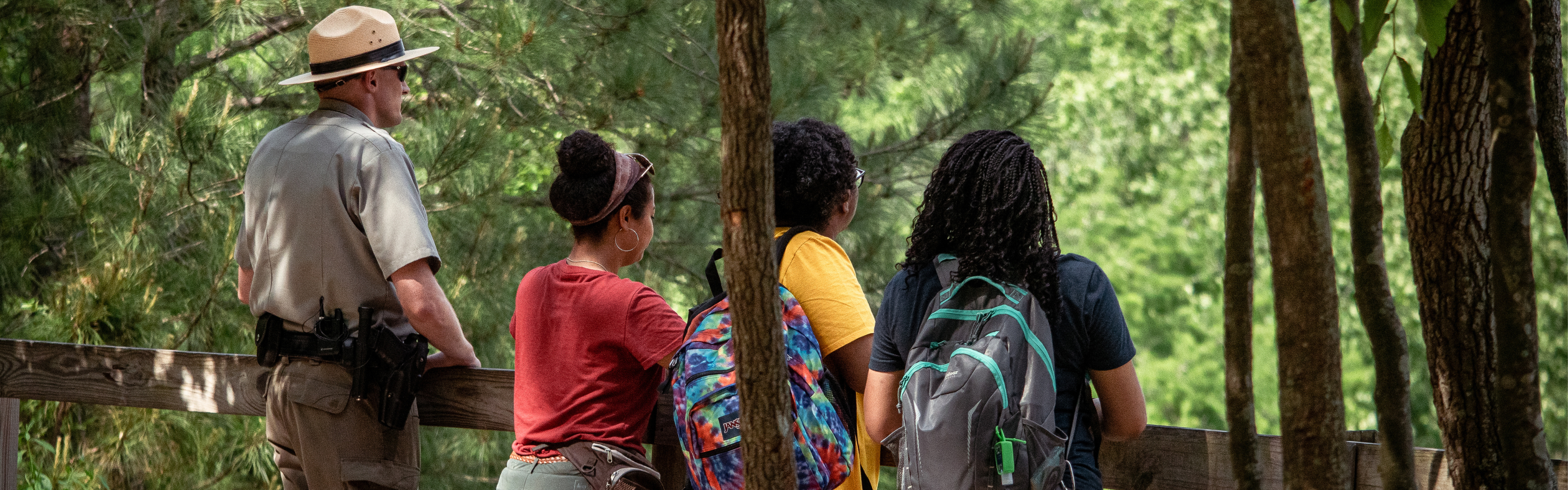 A ranger and hikers view a park overlook together.