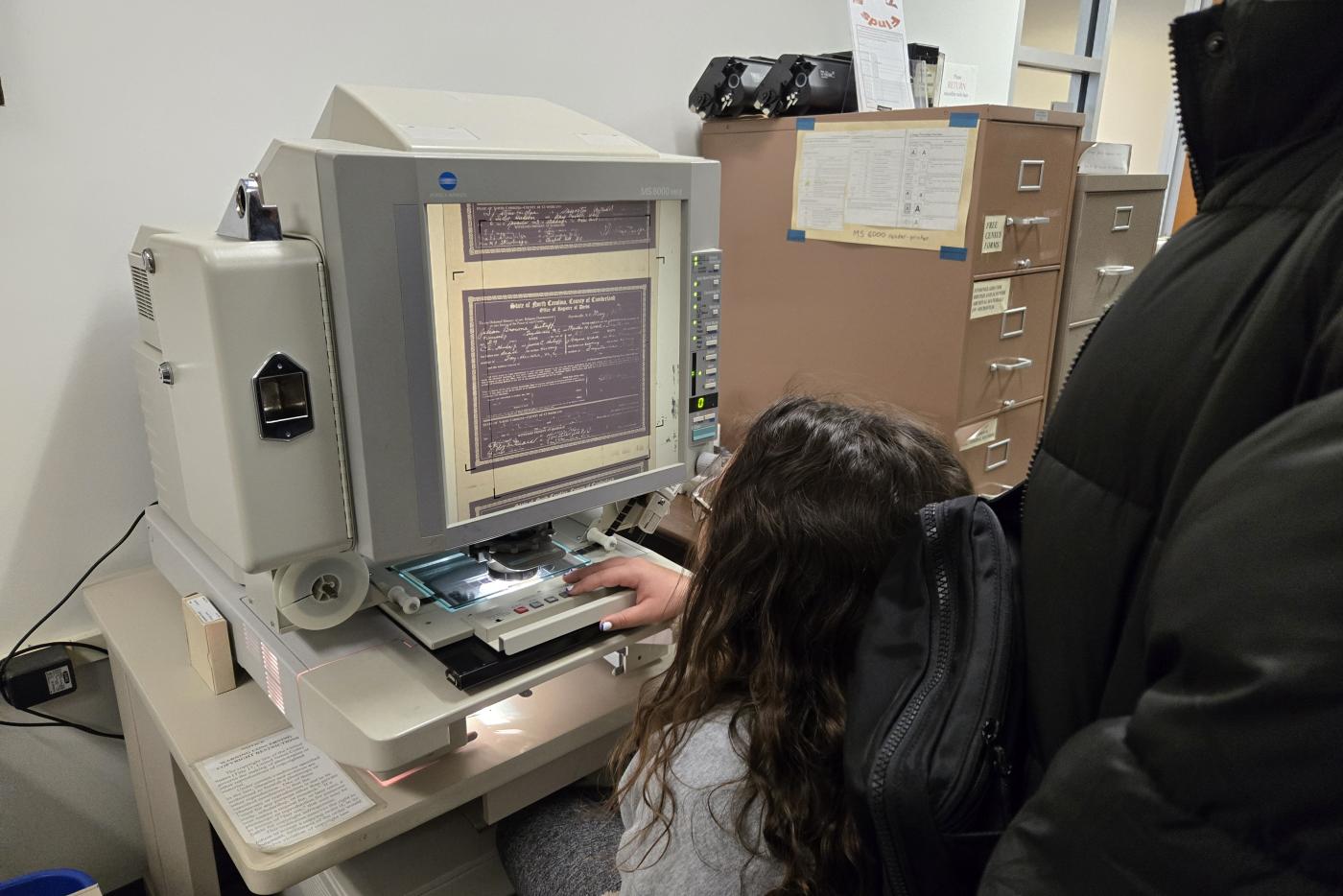A young student uses microfilm to look at historic documents.