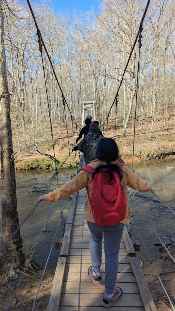 child crosses a bridge over a river