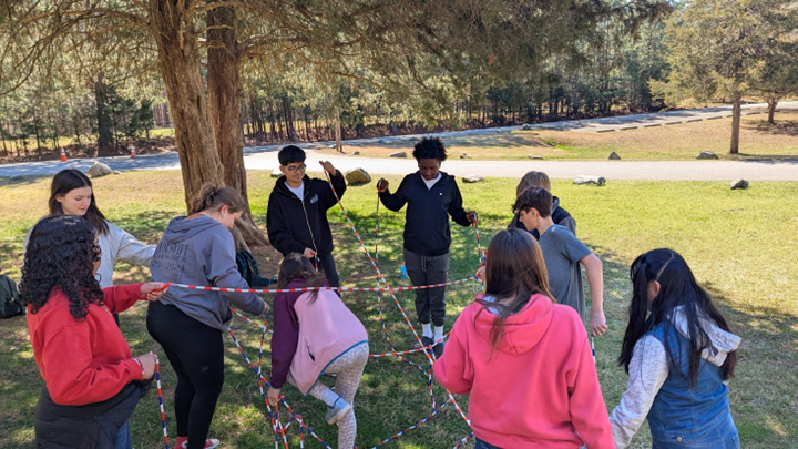 students working together to navigate a rope maze