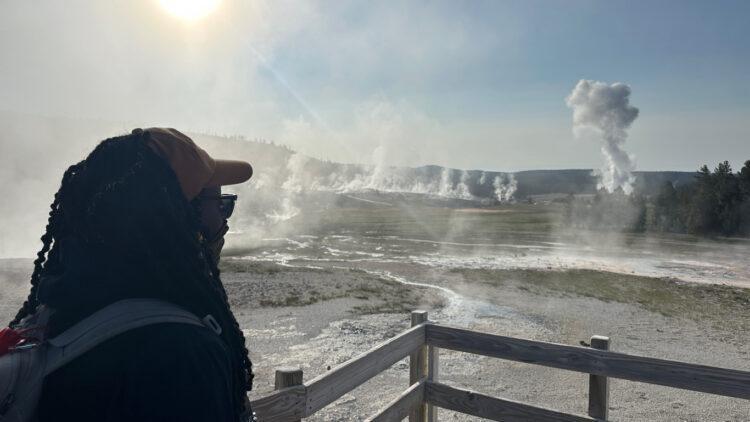 A teacher watches Old Faithful at Yellowstone.