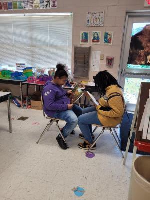 students reading a book while facing each other