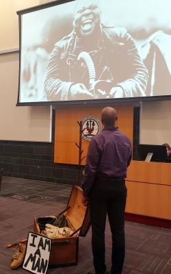 Sonny Kelly Looks up to a Photograph of a Black Veteran on Screen